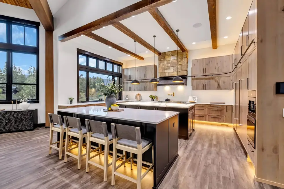 Vaulted kitchen with stained timber beams, two islands and a stone hood wall