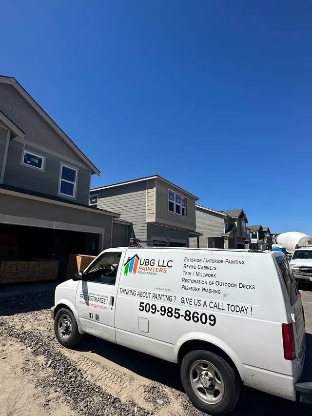 The UBG van at a new-build site, its side listing interior and exterior painting, cabinets, trim and millwork, deck restoration and pressure washing, with the licence number